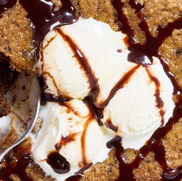 large chocolate chip cookie topped with vanilla ice cream and drizzled with chocolate sauce on top of a white platter