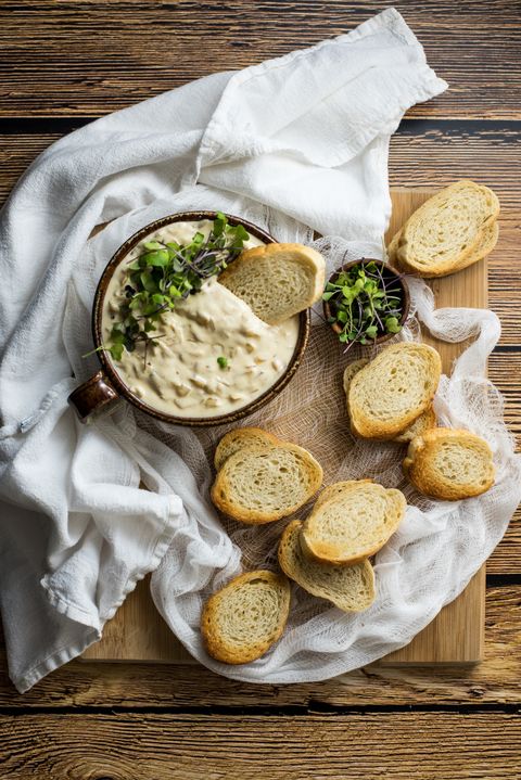 slow cooker french onion soup dip in mug with baguette slices on white linen