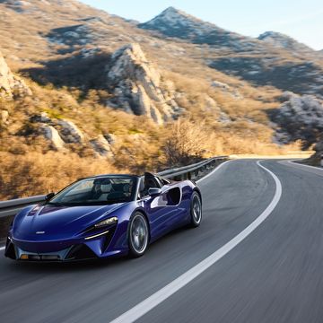 a blue sports car driving on a road in the mountains