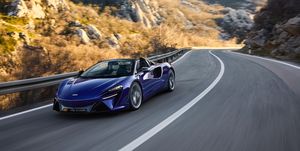 a blue sports car driving on a road in the mountains