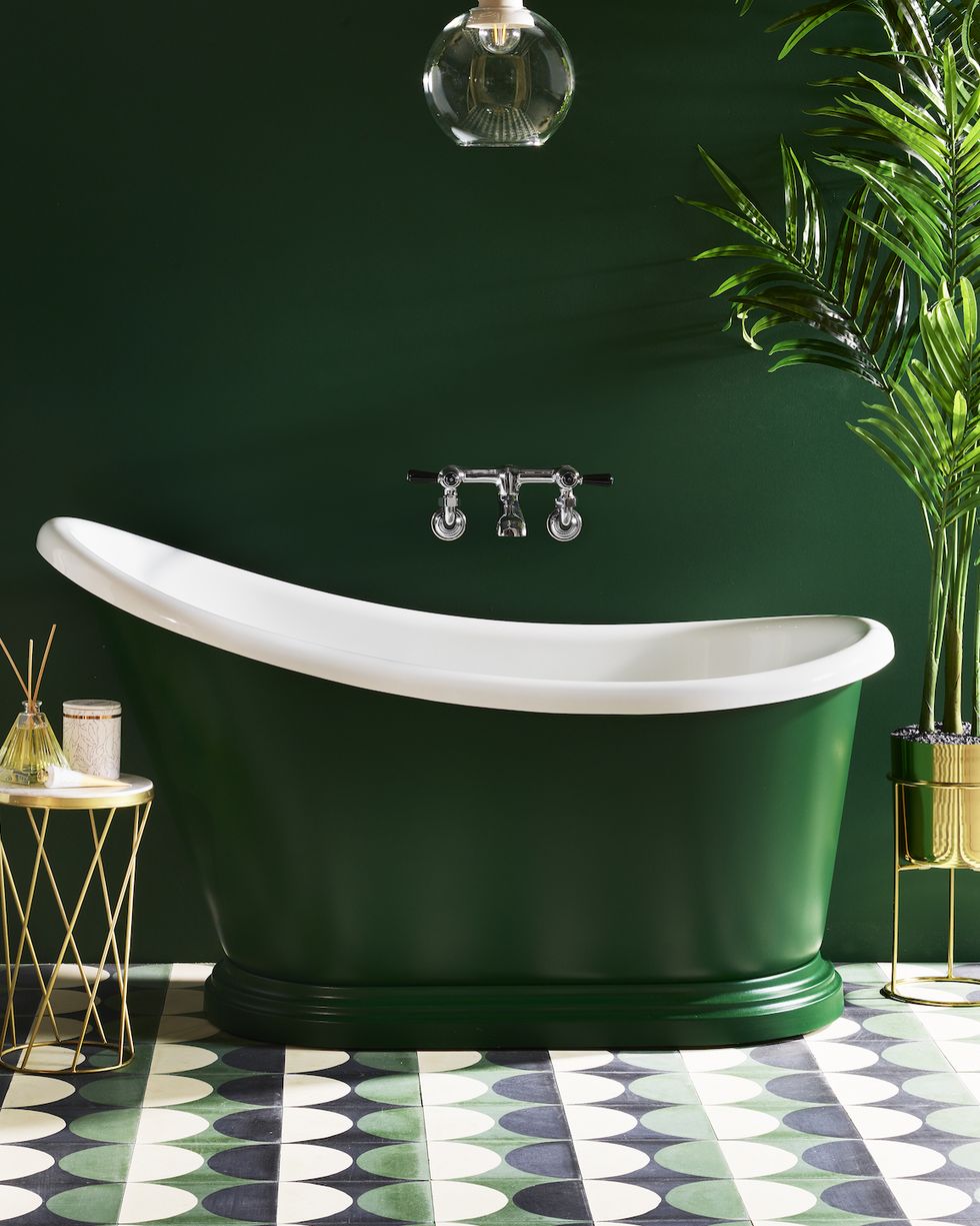an emerald green bathroom with matching small bath tub and geometric patterned tiles