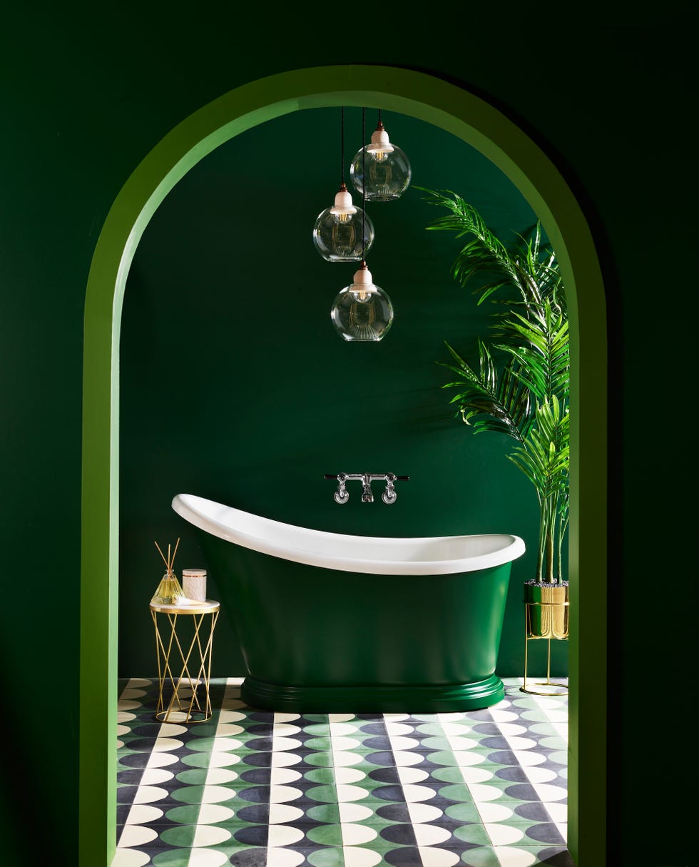 an emerald green bathroom with matching small bath tub and geometric patterned tiles