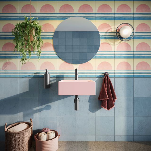a small bathroom with colourful tiles and a pastel pink basin