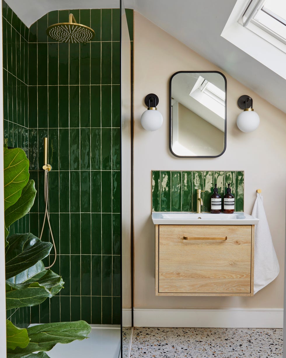 a small bathroom with sloped ceiling, walk in shower with green tiles, neutral walls and terrazzo flooring