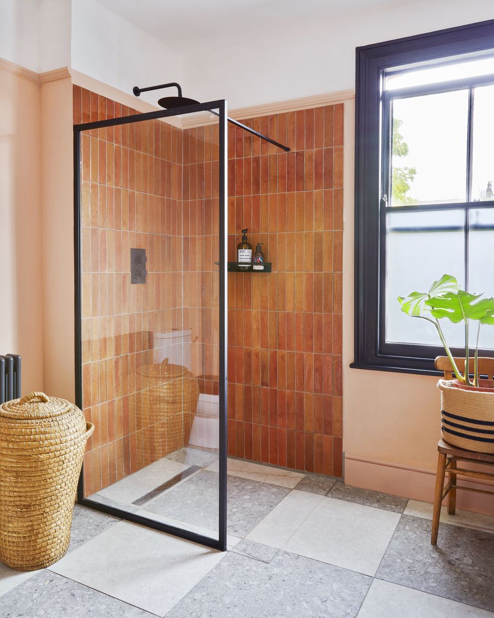 a small bathroom with checkerboard floor tiles, orange wall tiles and a walk in shower