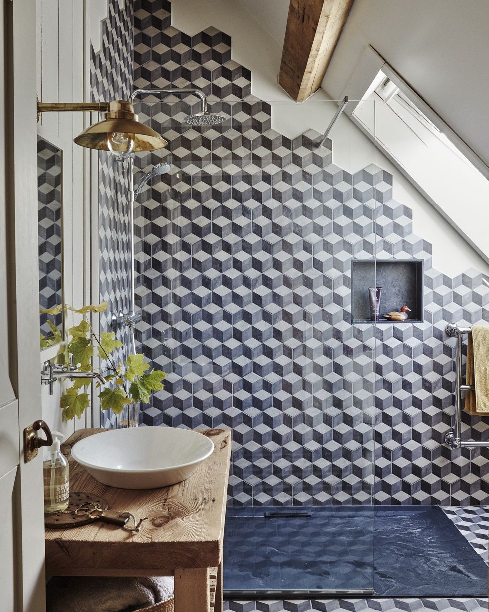 a small bathroom with sloping ceiling and irregular geometric tiles in a walk in shower