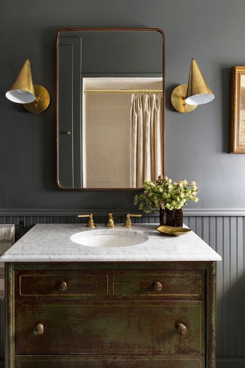 small dark bathroom with gold sconces