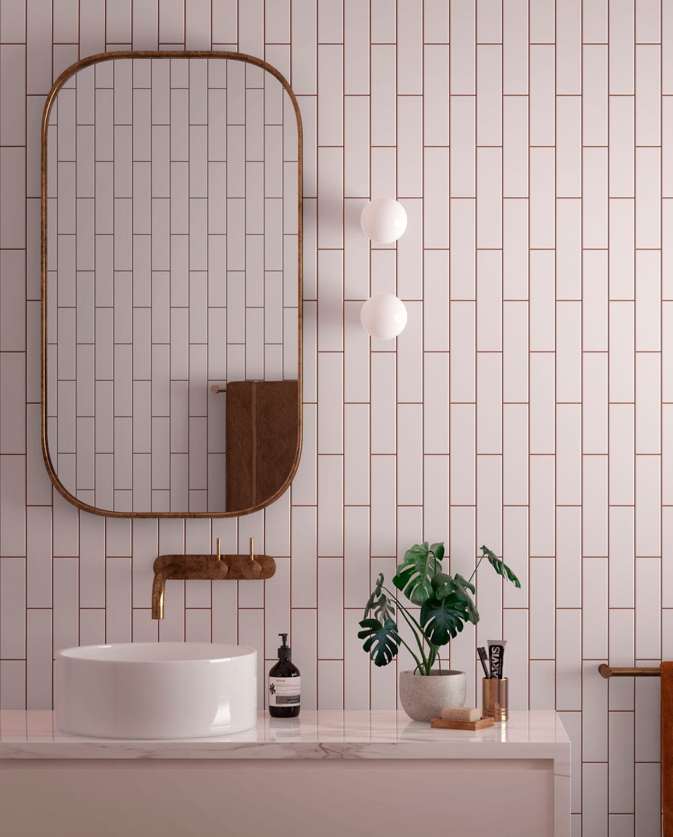 a small bathroom with pale pink metro tiles, a curved mirror and sink