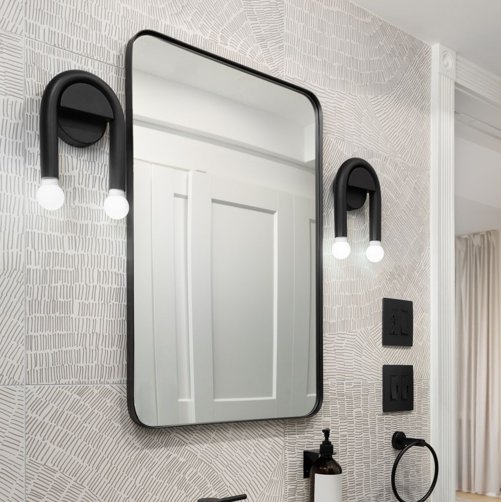 a small bathroom with pattern wallpaper and white oak cabinet.