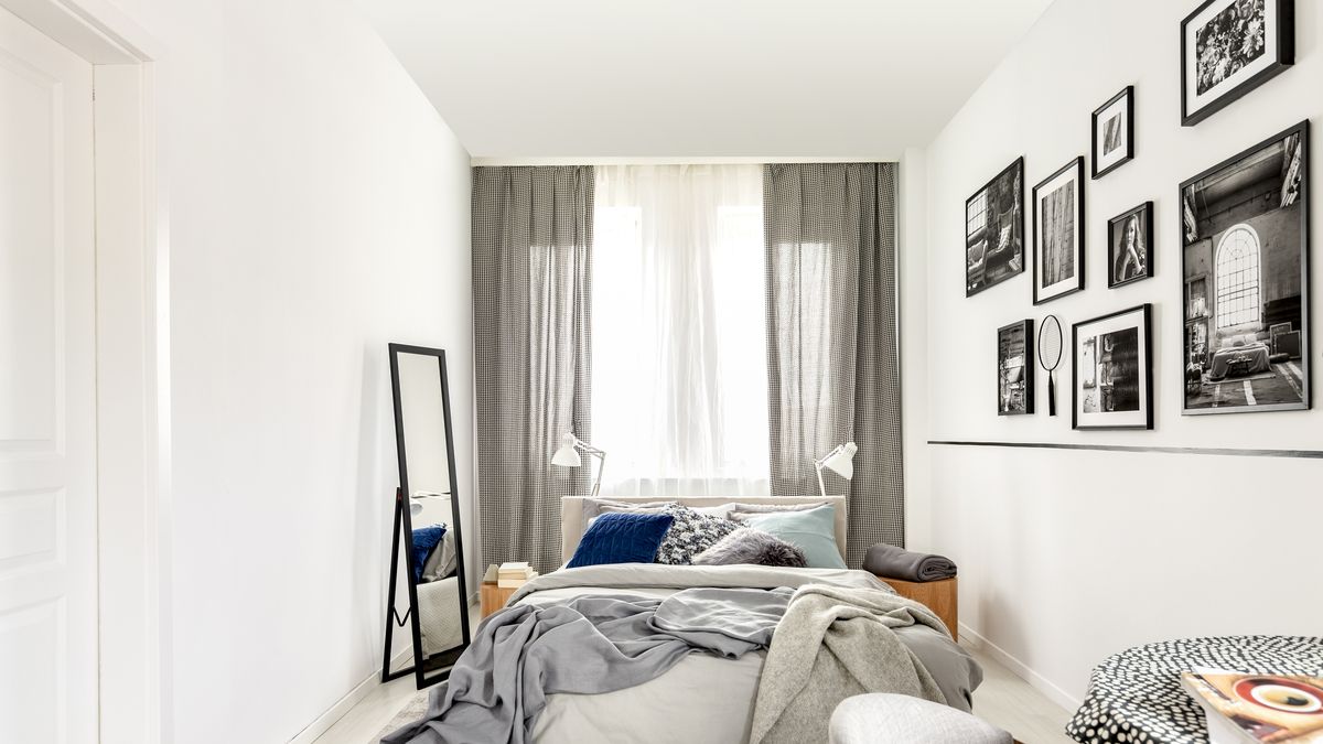 small bedroom interior with king size, mirror, and black and white photos on the wall