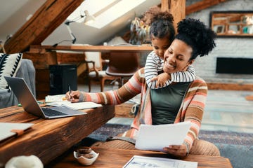 small black girl embracing her busy mother who is working at home