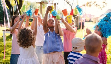 kids hanging up decorated party cups in the backyard