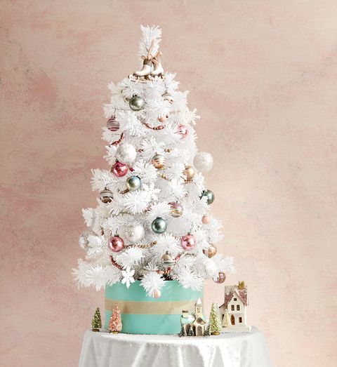 an all white spruce serves as an eye catching foundation for sparkling snowflakes and pastel baubles and putz house accents and a sweet ice skate topper