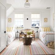 small couch or sofa in bedroom with two twin beds, white shiplap walls, and colorful striped rug