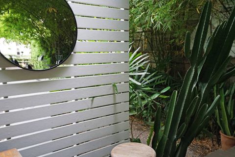 made of white wooden panels ,circular mirror and cactus plant pots