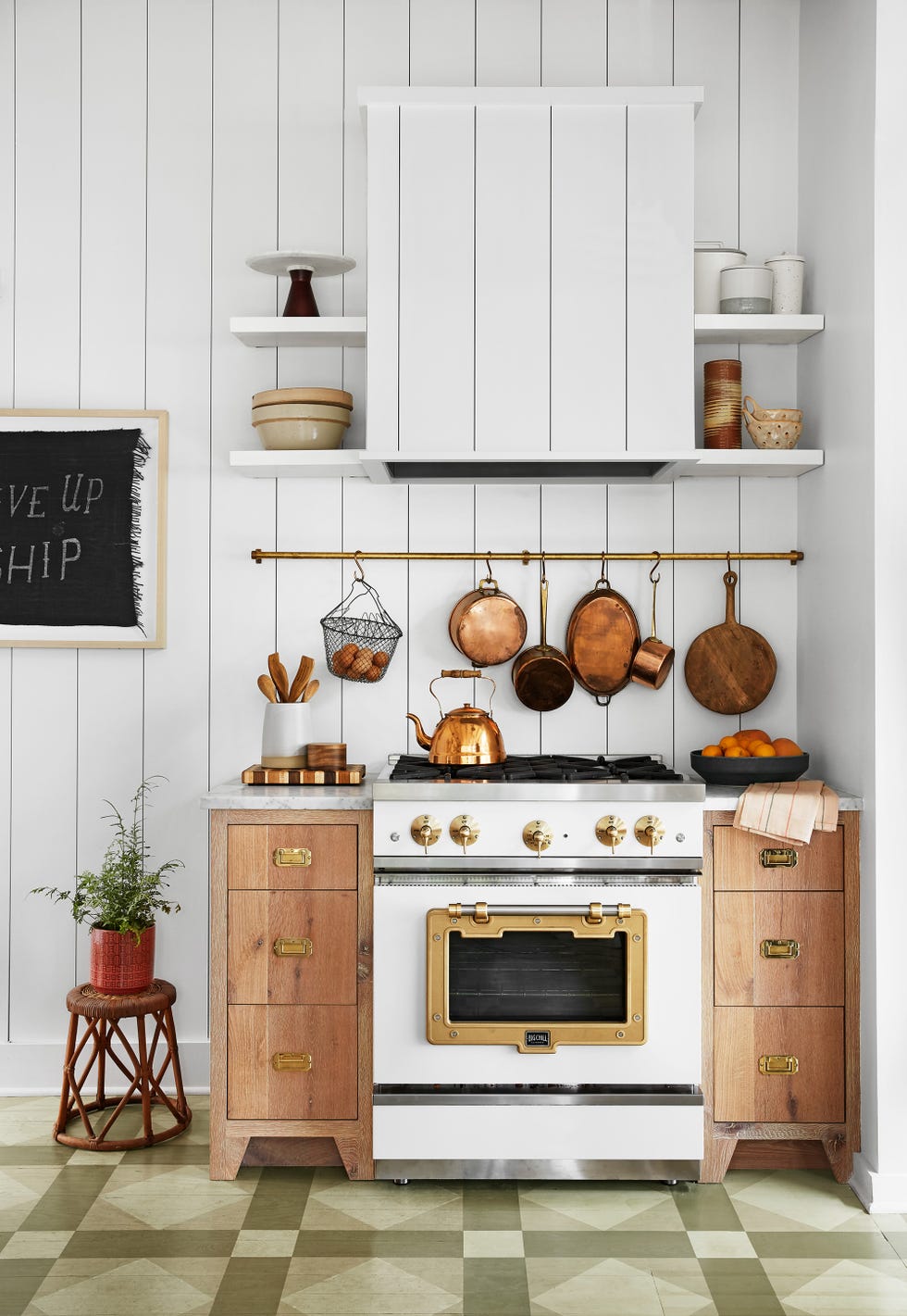 small white kitchen with brass pot rack above stove