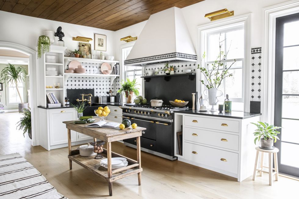 small rustic wood kitchen island with open bottom shelf in a white kitchen where a large black chef's oven is the showpiece