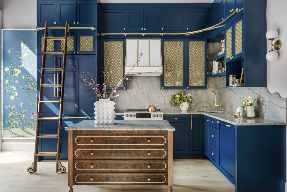 Navy and blue kitchen with brass accents and marble countertops by