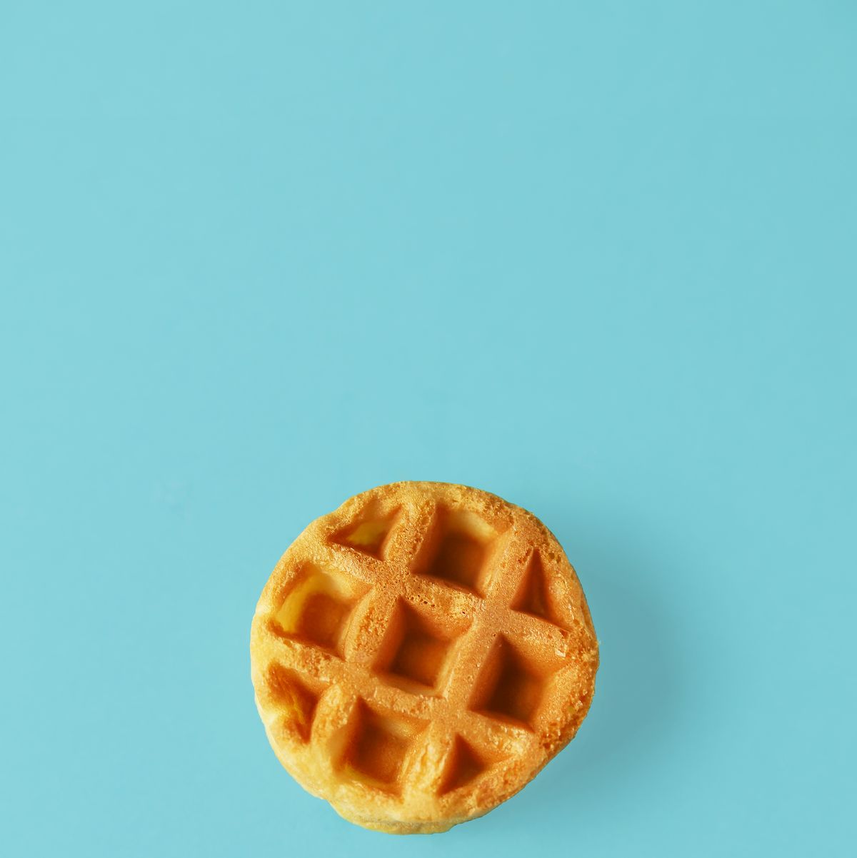 https://hips.hearstapps.com/hmg-prod/images/small-round-belgian-waffle-on-trendy-blue-royalty-free-image-1653068553.jpg?crop=1.00xw:0.668xh;0,0.170xh&resize=1200:*