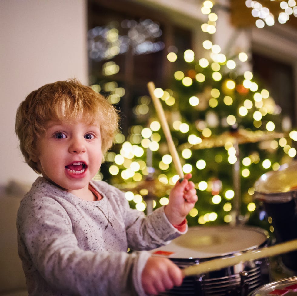 a small toddler boy playing drums indoors at christmas time