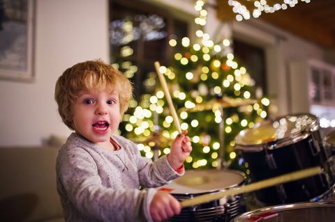 a small toddler boy playing drums indoors at christmas time