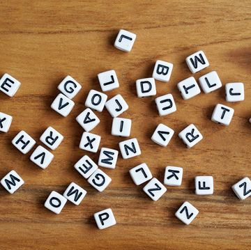 small white cube beads with various letters scattered on wooden board, view from above