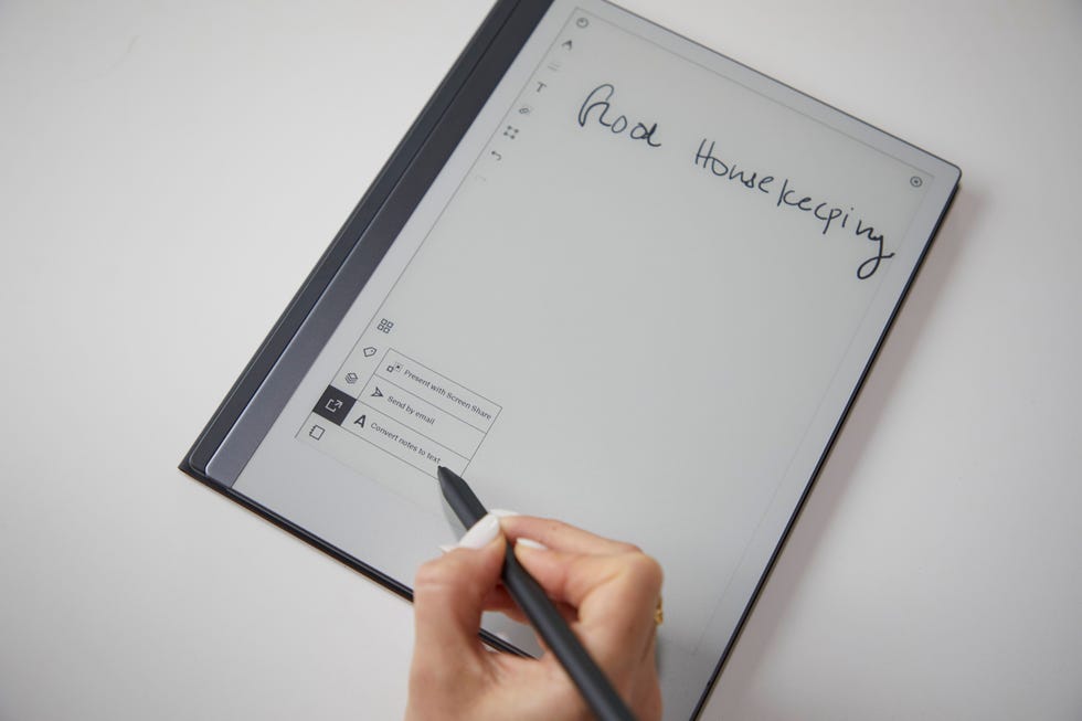 a hand holding a pen and a paper with writing on it