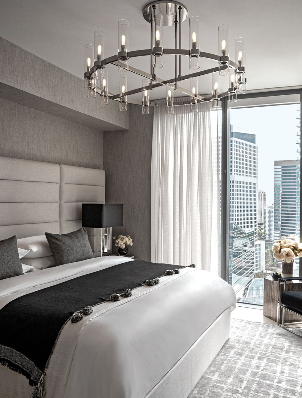 The master bedroom’s headboard, bedding, chandelier, table lamp, and rug are all by RH, Restoration Hardware. The wallcovering is by Phillip Jeffries.