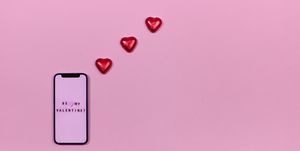 smartphone and heart shaped candies on pink background