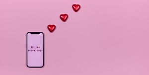 smartphone and heart shaped candies on pink background