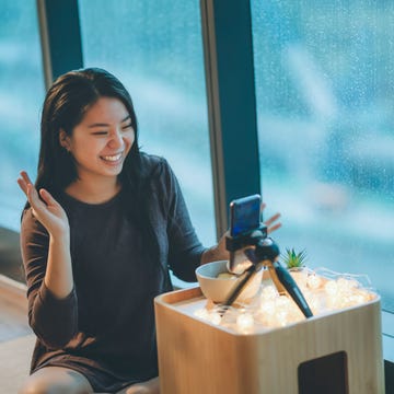 A person interacting with a smartphone camera setup in a cozy indoor environment A person interacting with a smartphone camera setup in a cozy indoor environment