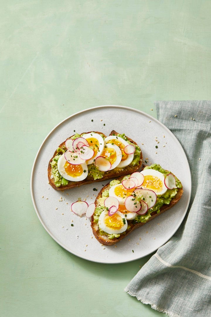 smashed avocado toast with jammy eggs and radish slices on top