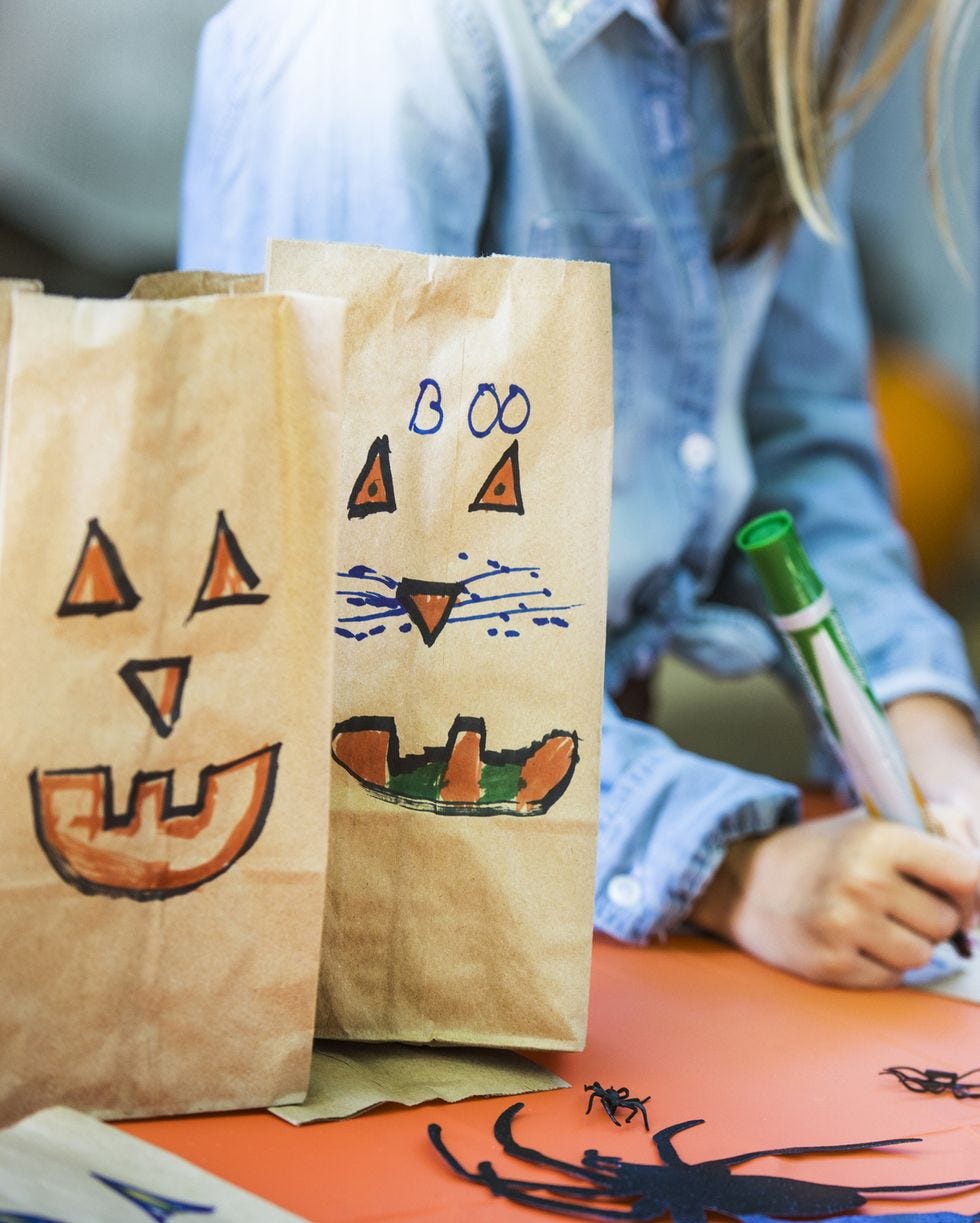 smiley faces on paper bags by siblings making art at table during halloween party
