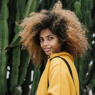 smiling afro woman standing by cactus in background