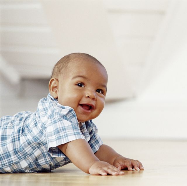 smiling baby boy crawling across the floor