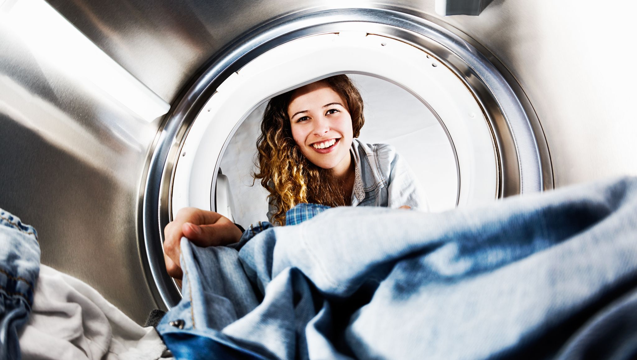 Smiling blonde beauty loads her tumble dryer: seens from inside