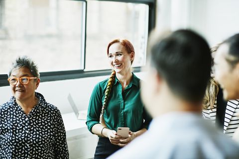smiling businesswoman listening during team meeting in office