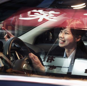 smiling businesswoman pointing out of the car while driving through beijing at night