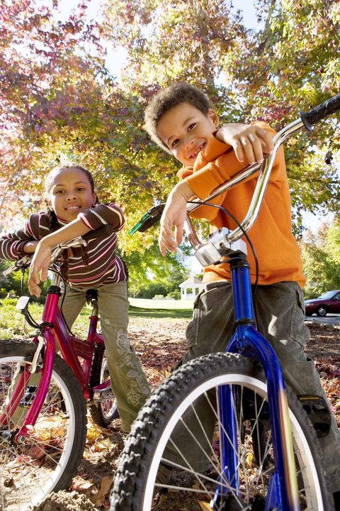 smiling children riding bikes in autumn park at camera