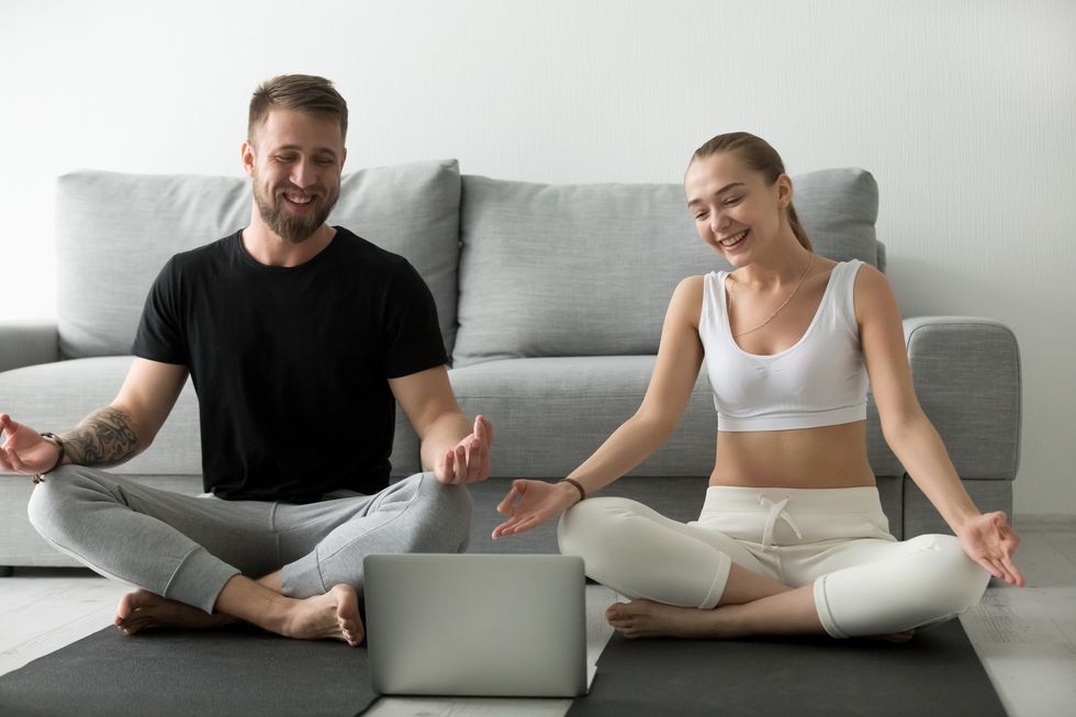 Smiling couple learning yoga exercises watching video on laptop