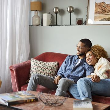 smiling couple looking away while sitting on sofa