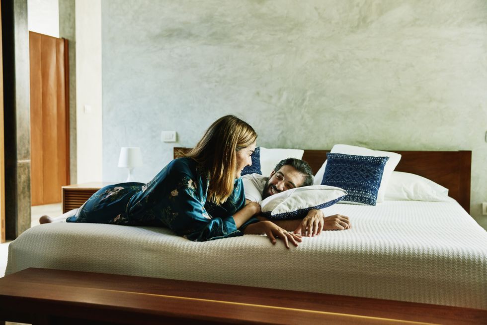smiling couple relaxing on bed at luxury hotel