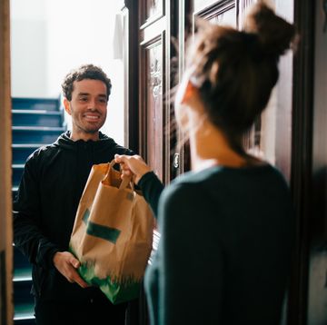 smiling delivery man delivering bag to woman standing at doorway