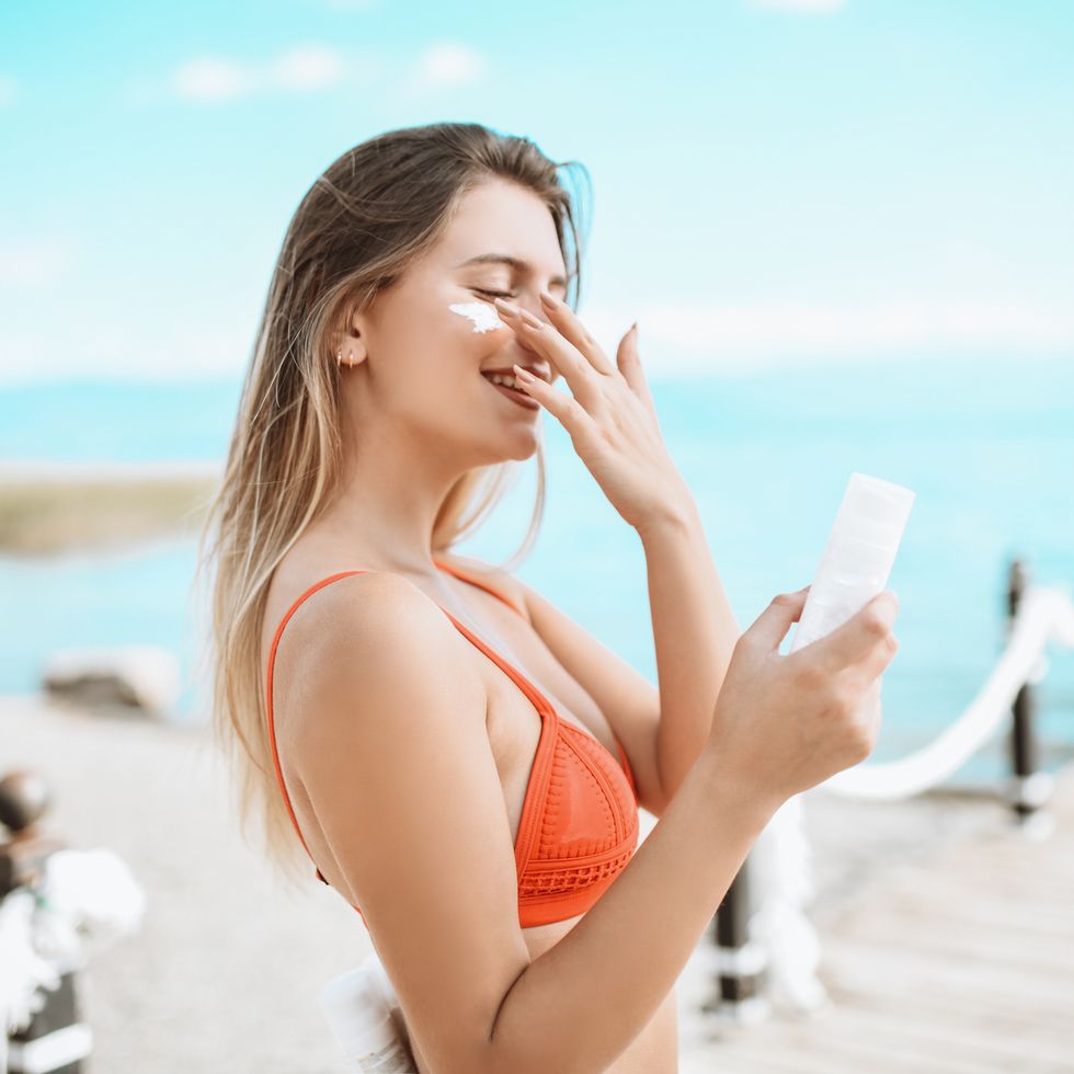 smiling female beauty and her favorite sunscreen at the beach