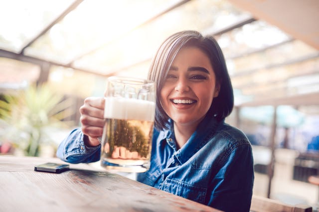 smiling female drinking beer in city pub on a sunny day