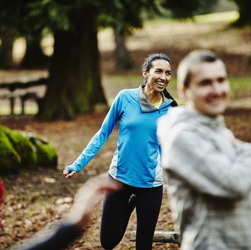 Smiling female runner stretching with friends