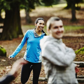 Smiling female runner stretching with friends