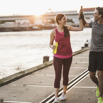 smiling friends giving high five while walking at harbor