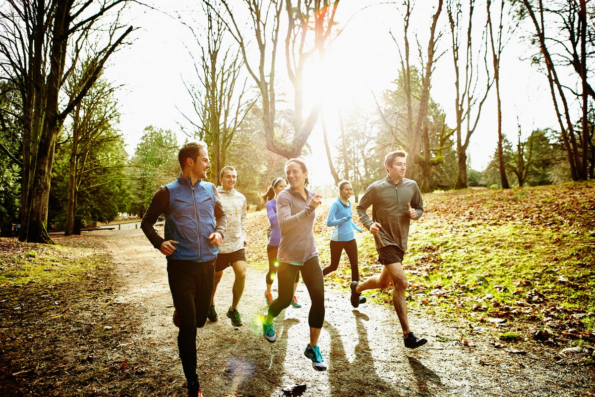 smiling friends running together in park