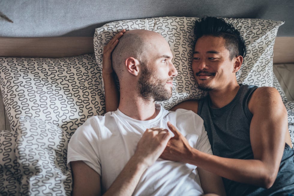 smiling gay couple laying on bed